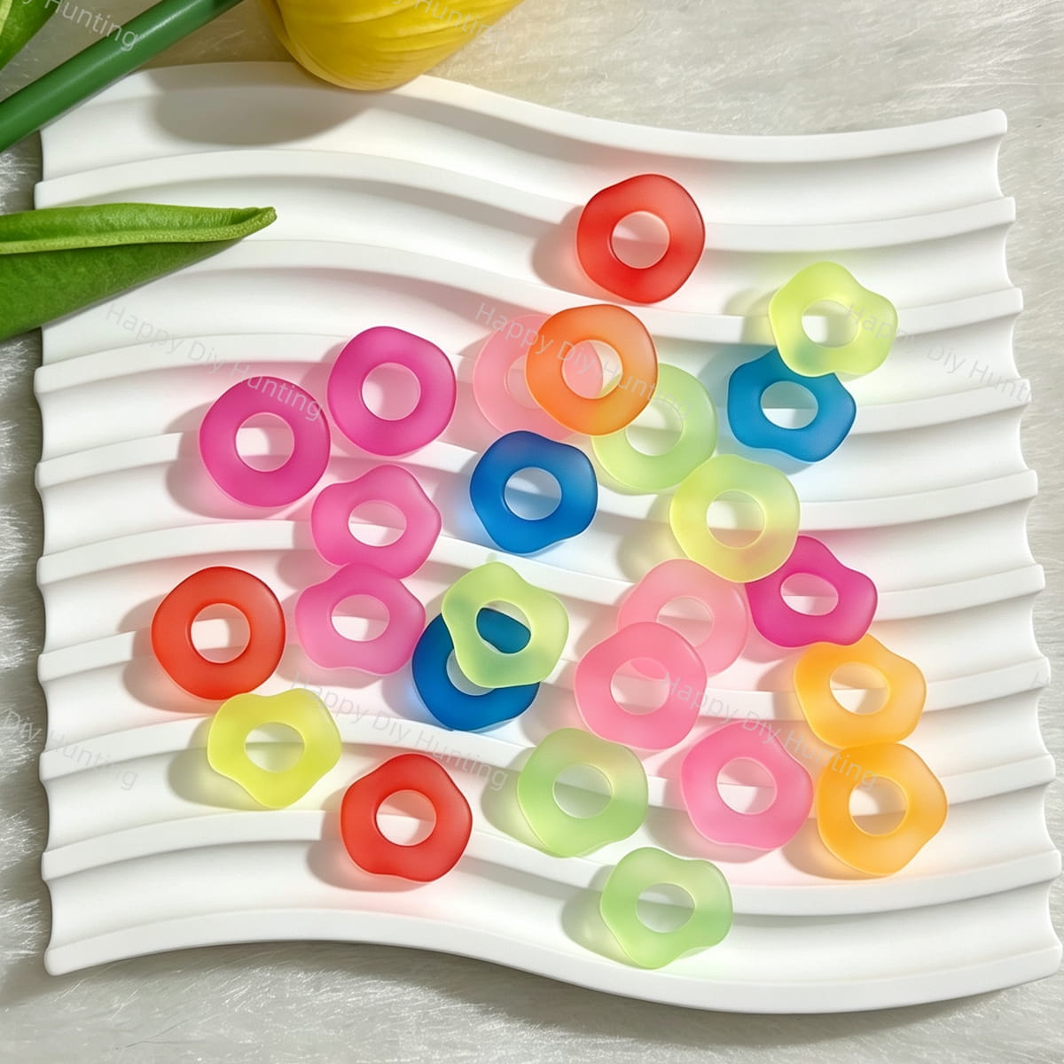 A mix of 16mm matte frosted acrylic spacer beads in round and flower shapes. Colors include pink, orange, blue, green, yellow, and red with a soft translucent finish. Displayed on a white wavy tray. Perfect for jewelry making, beadable pens, and handmade crafts.