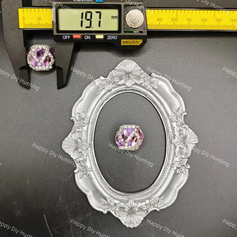 A silver oval frame displaying a purple gemstone ring, with a caliper above showing the ring's width as 19.7 mm.