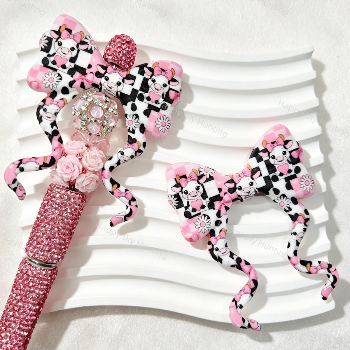 Bow-shaped silicone focal beads featuring a pink cartoon cow and daisy print design. Soft, durable, and flexible, perfect for beadable pens, keychains, and handmade crafts