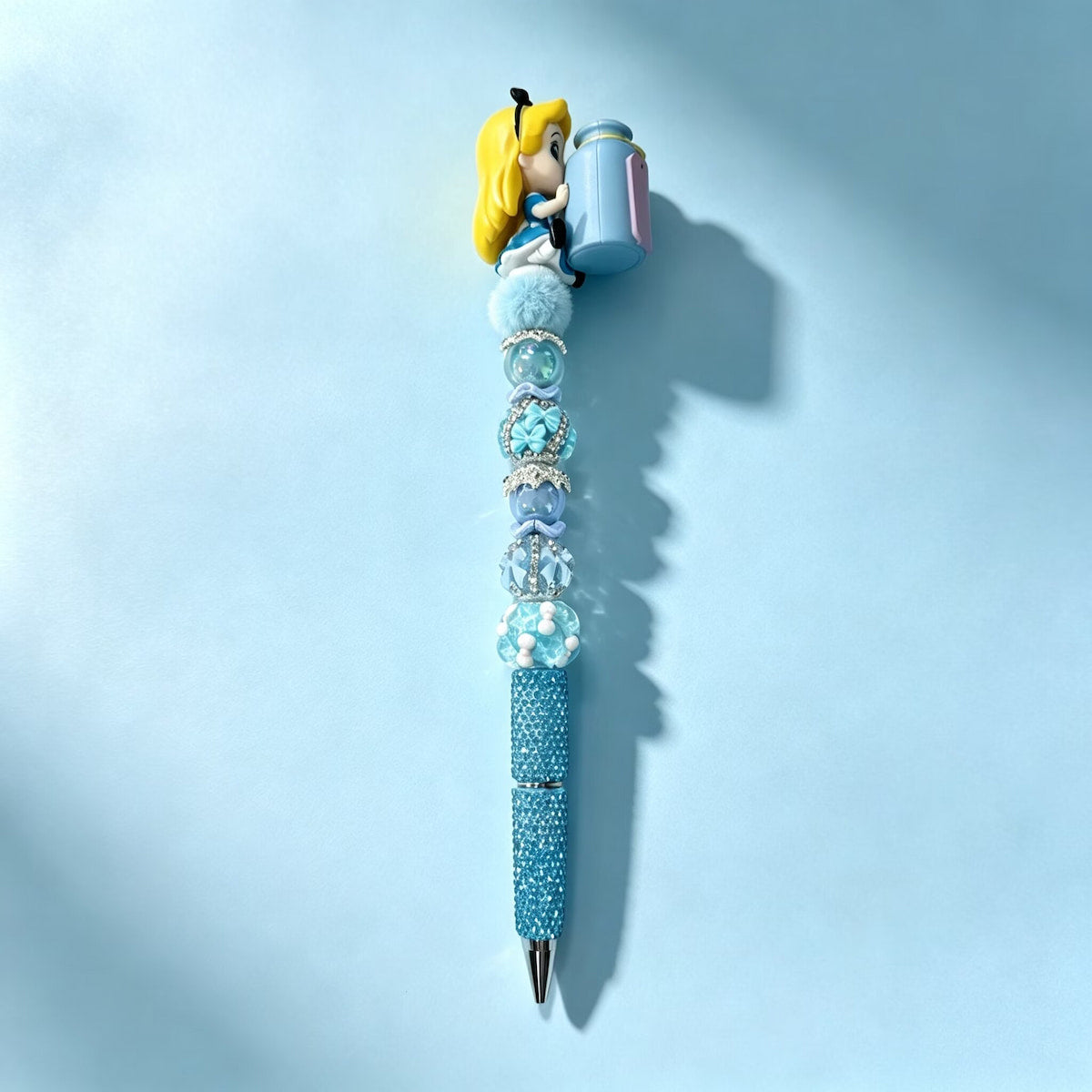 Sample display beadable pen decorated with Alice In Wonderland themed no‑hole pen toppers and assorted beads