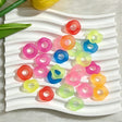 A mix of 16mm matte frosted acrylic spacer beads in round and flower shapes. Colors include pink, orange, blue, green, yellow, and red with a soft translucent finish. Displayed on a white wavy tray. Perfect for jewelry making, beadable pens, and handmade crafts.