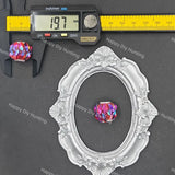 A faceted iridescent crystal bead shown with a silver ornate oval frame and a digital caliper on a dark gray background. The caliper reads 19.
