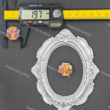 A faceted round crystal bead with an iridescent rainbow finish, displayed next to a digital caliper showing 19.7 mm measurement and centered inside an ornate silver oval frame on a dark gray background.