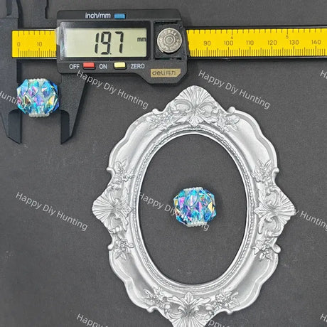 An ornate silver oval picture frame displayed on a dark gray background, with a small iridescent blue-purple crystal bead shown inside the frame. A digital caliper is positioned above the frame to show measurements, and the brand name Happy DIY Hunting is watermarked across the image.