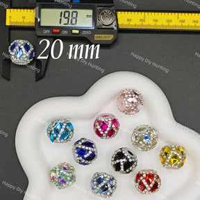 Ten 20mm round crystal beads in various colors and patterns arranged on a white heart-shaped tray, with a digital caliper showing 19.8 mm and a larger blue bead shown separately.