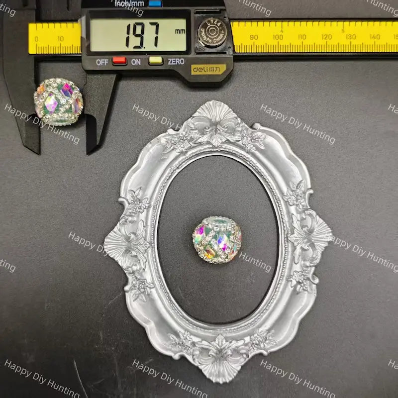 A round crystal cabochon gemstone displayed in a silver ornate oval frame, with a digital caliper measuring 19.7mm shown at the top left on a dark gray background with watermarks.