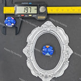 A small blue and white beaded ornament with a tiny orange accent is shown inside an ornate silver oval frame, alongside a caliper measuring 19.7 mm and a yellow ruler on a dark gray background.