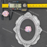 An ornate silver oval frame displayed on a dark gray background, with a pink iridescent bead shown inside the frame and a digital caliper above it measuring 19.7 mm.