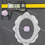 A small iridescent lavender and pink flower-shaped bead or charm displayed on a dark gray background, with a silver ornate oval frame, a yellow caliper, and a digital ruler above it. Repeated 'Happy Diy Hunting' watermarks are visible across the photo.