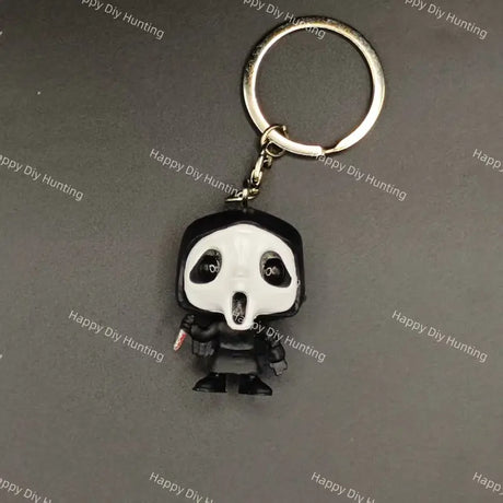 A keychain featuring a stylized, cartoonish figure with a black and white mask, black robe, and silver metal key ring and chain, shown on a dark gray background with repeating 'Happy DIY Hunting' watermarks.