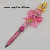 Pink handmade pre-assembled bead pen with Aurora princess figure, pink satin bow, shiny rhinestone focal beads, glitter crystal pen barrel for boutique resellers