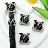 Black metal fancy beads featuring a designer V*L letter design with a rhinestone border, displayed with a black rhinestone beadable pen. Sturdy, shiny, and glamorous, perfect for beadable pens, keychains, and handmade crafts.