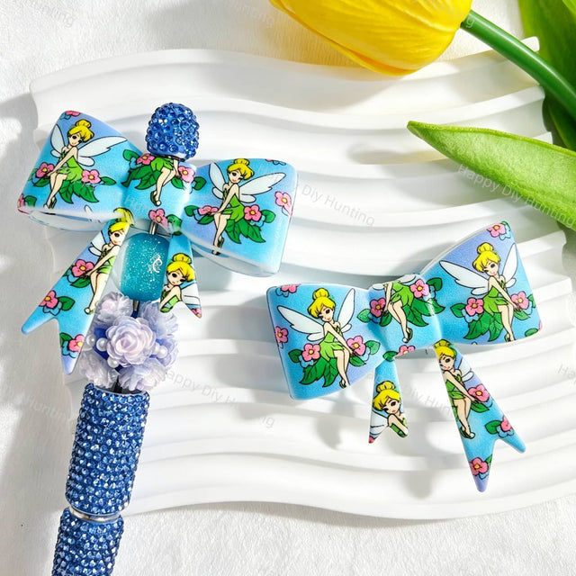 Bow-shaped silicone focal beads featuring a blue winged fairy girl and floral print design. Soft, durable, and flexible, perfect for beadable pens, keychains, and handmade crafts.