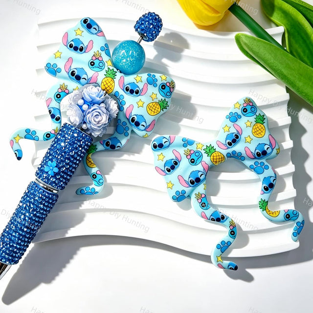 Bow-shaped silicone focal beads featuring a blue alien and pineapple print design. Soft, durable, and flexible, perfect for beadable pens, keychains, and handmade crafts.