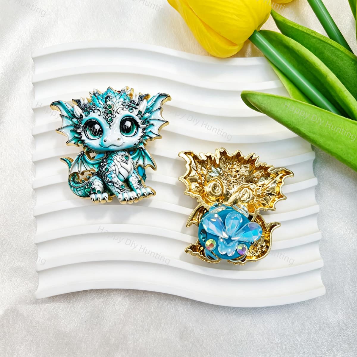 Blue and white cute baby dragon metal fancy bead with rhinestones shown from the front and back. The front features a detailed blue and white baby dragon with big eyes and rhinestone accents, while the back shows gold metal wings with a blue crystal flower center. Perfect for DIY beadable pens and crafts.