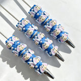 Close-up of four blue bunny cartoon character beadable pens on a white background. Each pen features blue beads decorated with bunny faces and white faux pearls, paired with silver metal tips. Ideal for DIY beadable pen projects, focal beads, and pen toppers.