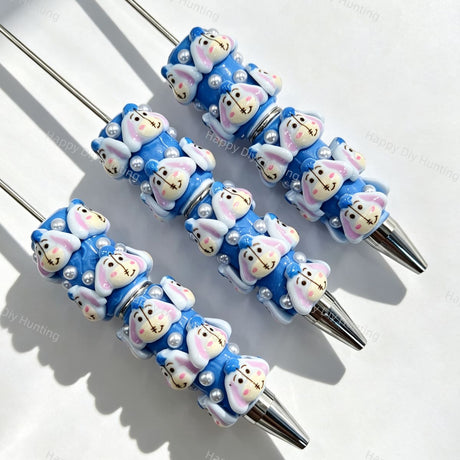 Close-up of four blue bunny cartoon character beadable pens on a white background. Each pen features blue beads decorated with bunny faces and white faux pearls, paired with silver metal tips. Ideal for DIY beadable pen projects, focal beads, and pen toppers.