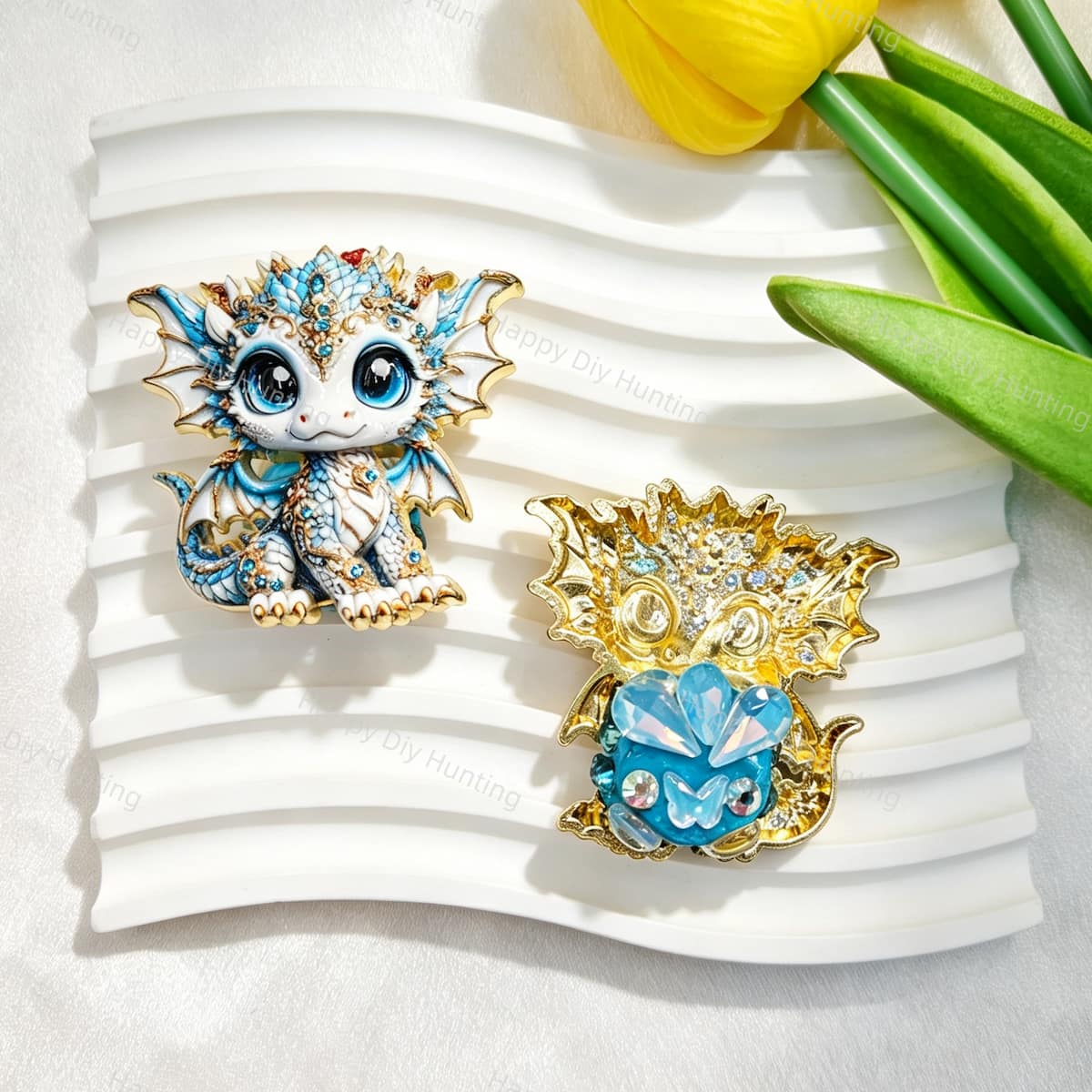 Blue cute baby dragon metal fancy bead with rhinestones shown from the front and back. The front features a detailed blue and white baby dragon with big eyes and rhinestone accents, while the back shows gold metal wings with a blue crystal flower center. Perfect for DIY beadable pens and crafts.