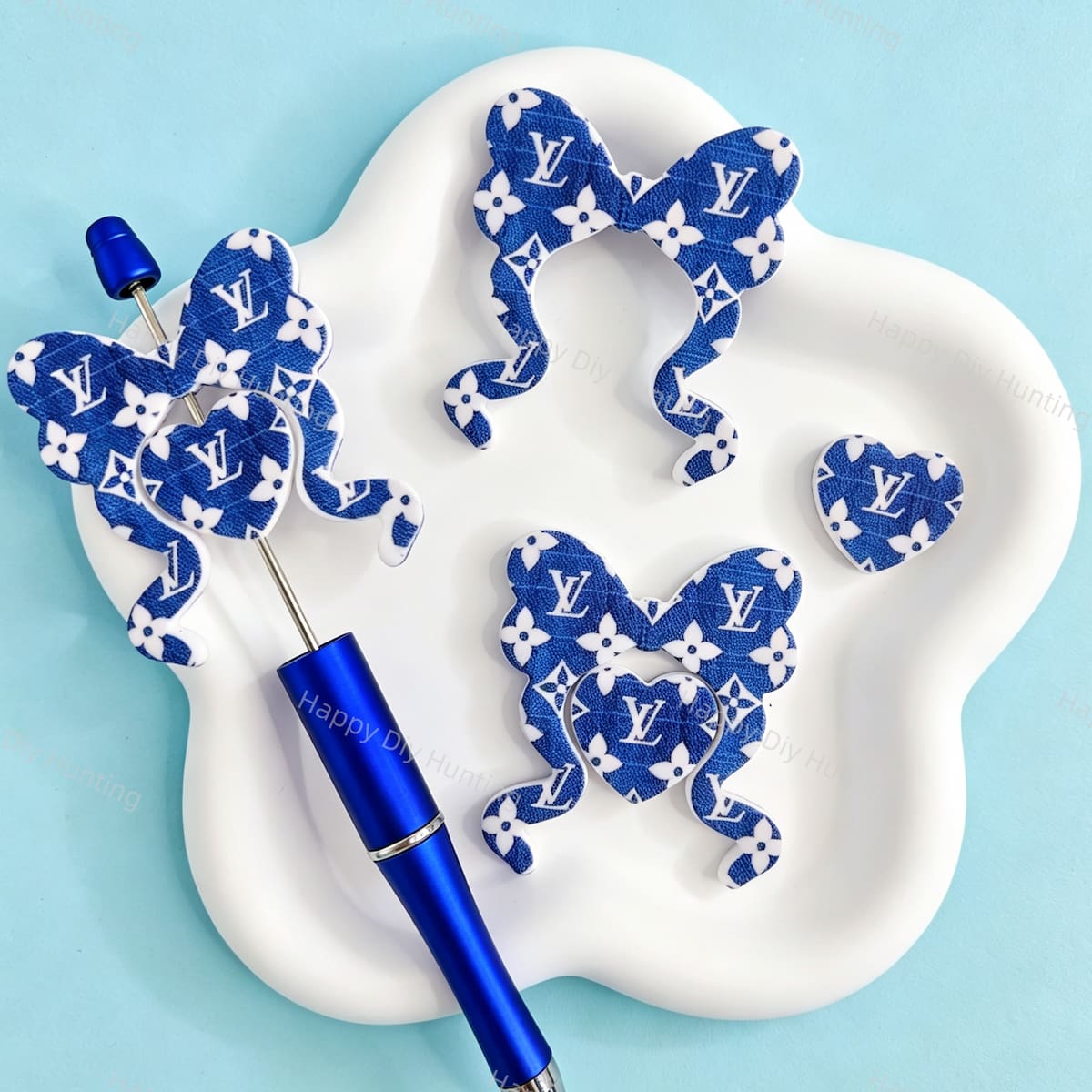 Bow-shaped silicone focal beads featuring a blue fabric texture and V*L monogram pattern design. Soft, durable, and flexible, perfect for beadable pens, keychains, and handmade crafts.