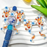 Blue highland cow floral print silicone bow beads displayed with a blue rhinestone beadable pen. Featuring an adorable highland cow with a bow and blue flowers. Soft, durable, and perfect for beadable pens, keychains, and handmade crafts