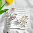 White bow-shaped silicone focal beads with colorful cartoon dog designs, including dogs wearing sunglasses, chef hats, and bow ties. Shown with a rhinestone beadable pen and a pink round bead. Perfect for beadable pens, keychains, and handmade crafts.