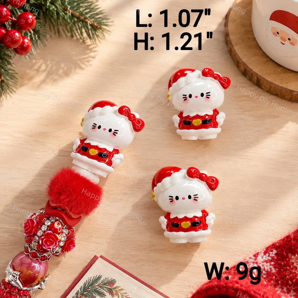 A Christmas cartoon kitty clay pen topper featuring a red Santa outfit with a red bow and white trim. Measures 1.07" L x 1.21" H and weighs 9g. Solid clay topper with no pre-drilled holes, perfect for custom beadable pens and DIY crafts.