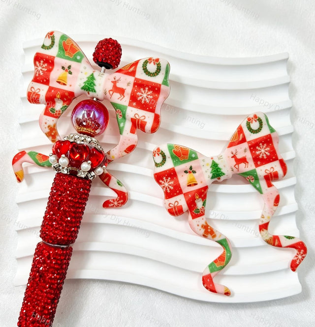 Bow-shaped silicone focal beads featuring a festive Christmas patchwork grid print with reindeer, Christmas tree, and snowflake elements. Soft, durable, and flexible, perfect for beadable pens, keychains, and handmade holiday crafts.