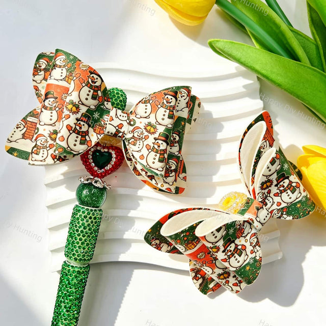 Bow-shaped beads featuring a Christmas snowman print design. Lightweight, festive, and durable, perfect for beadable pens, keychains, and handmade holiday crafts.