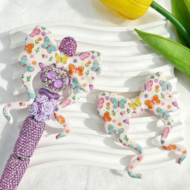 Bow-shaped silicone focal beads featuring a colorful butterfly and floral print design. Soft, durable, and flexible, perfect for beadable pens, keychains, and handmade crafts.