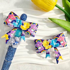 Bow-shaped silicone focal beads featuring a colorful rainbow cartoon bear print design. Soft, durable, and flexible, perfect for beadable pens, keychains, and handmade crafts.