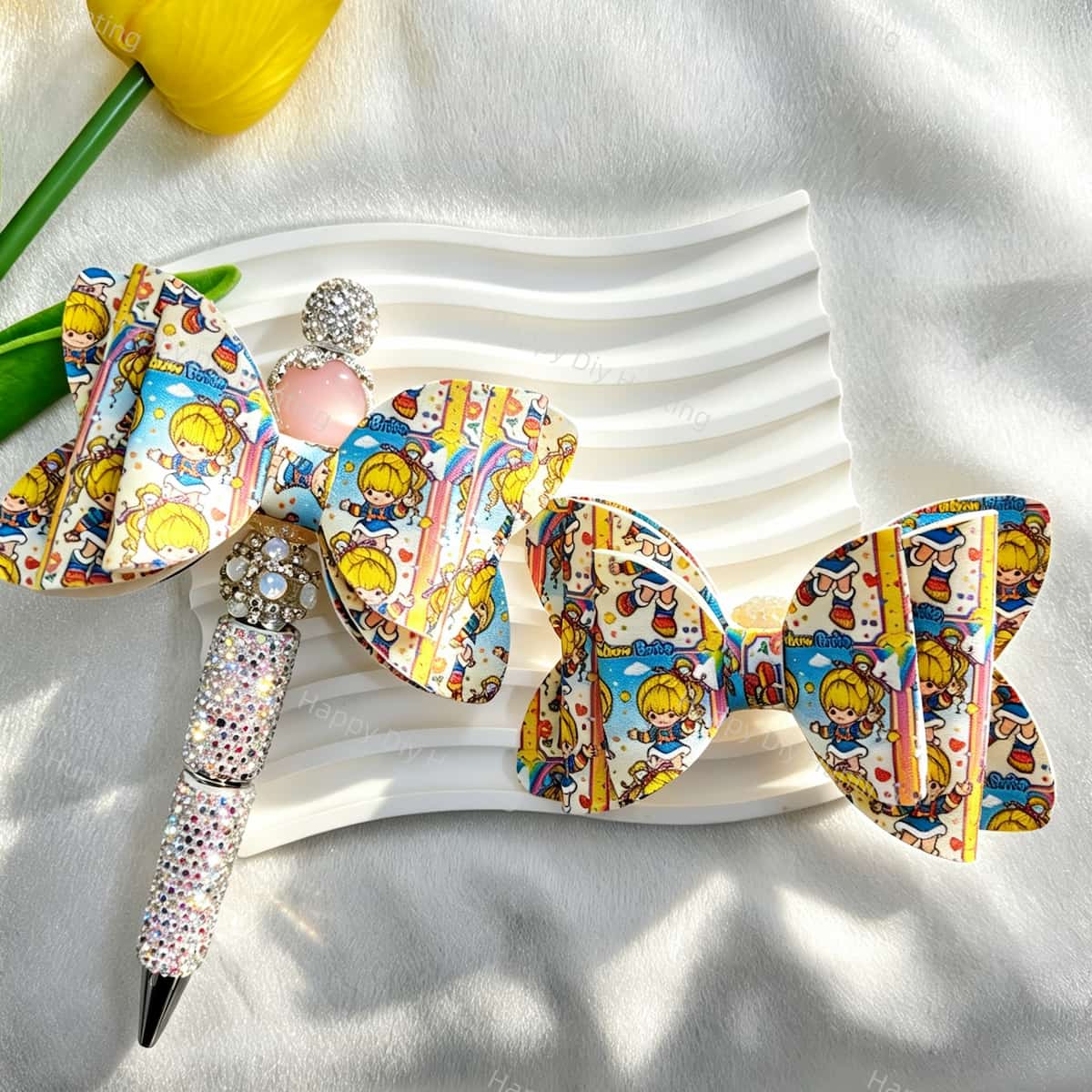 White bow-shaped PU leather focal beads with colorful cartoon girl designs. Shown with a rhinestone beadable pen and a pink round bead. Perfect for beadable pens, keychains, and handmade crafts.