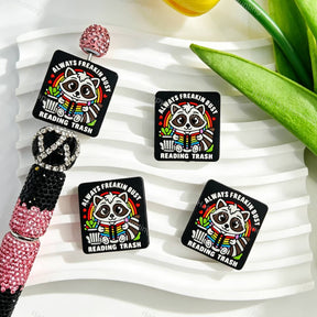 Silicone focal beads featuring a cute raccoon reading a book with a quote print design. Soft, durable, and flexible, perfect for beadable pens, keychains, and handmade crafts.