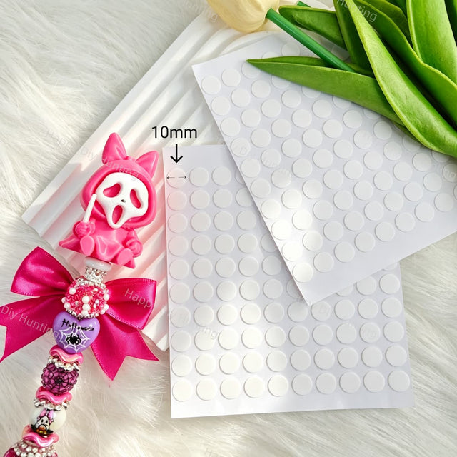 Clear double sided adhesive dots for securing beads, charms, and decorations on beadable pens and handmade crafts. Peel-and-stick, mess-free, and easy to use.