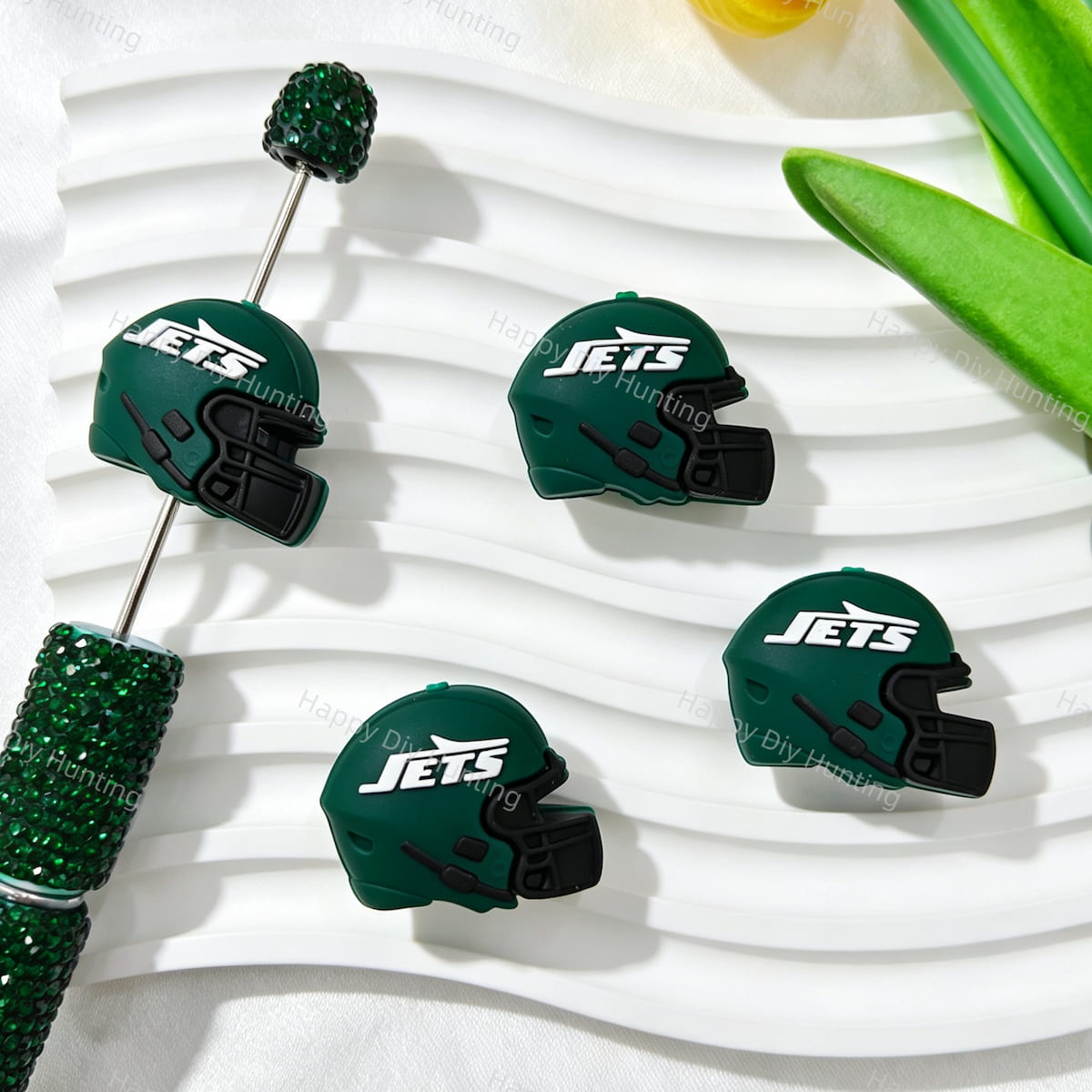 Four green 3D football helmet silicone focal beads displayed with a green rhinestone beadable pen. Soft, durable, and flexible, perfect for sports-themed beadable pens, keychains, and handmade crafts.