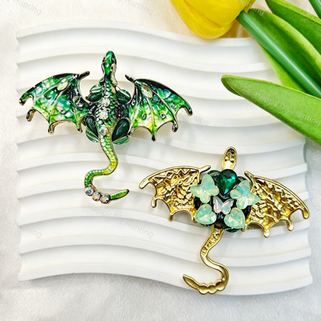 Green flying winged dragon metal fancy bead with rhinestones shown from the front and back. The front features a detailed green dragon with enamel wings and a rhinestone-studded body, while the back shows gold metal wings with a green crystal flower center. Perfect for DIY beadable pens and crafts.