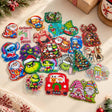 A large collection of mixed Christmas-themed acrylic flatback charms on a light surface. Features various designs including green characters with Santa hats, blue aliens, gnomes, Santa Claus, and Christmas trees. Perfect for holiday DIY crafts, beadable pens, and decorations.
