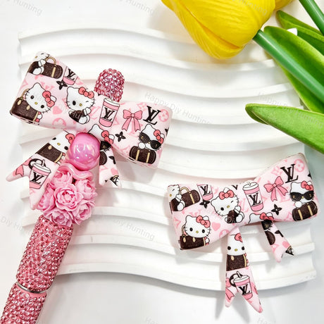 Bow-shaped silicone focal beads featuring a pink cartoon kitten and V*L print design. Soft, durable, and flexible, perfect for beadable pens, keychains, and handmade crafts.