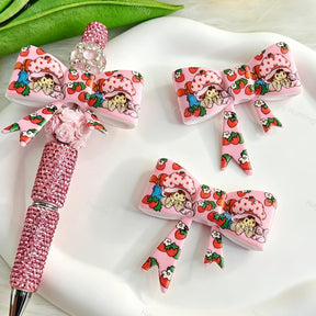 Bow-shaped silicone focal beads featuring a pink cute strawberry girl cartoon design. Soft, durable, and flexible, perfect for beadable pens, keychains, and handmade crafts.