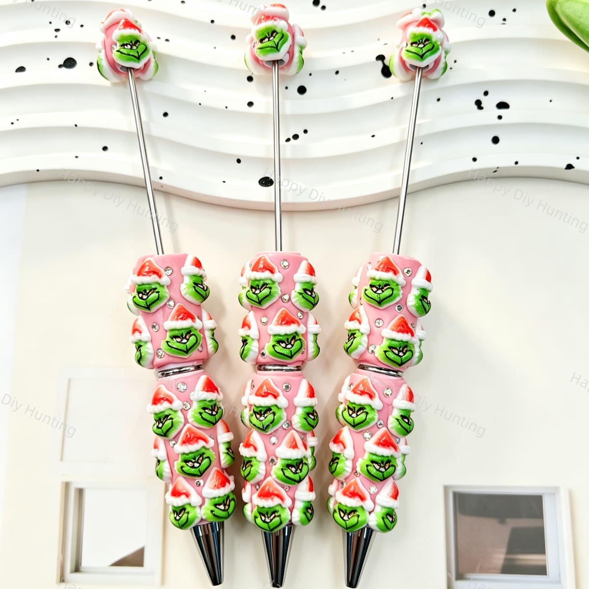 Three pink beadable pens featuring a green cartoon character wearing a Santa hat and clear rhinestones. Equipped with silver metal tips. Perfect for DIY beadable pen projects, focal beads, and handmade holiday crafts.