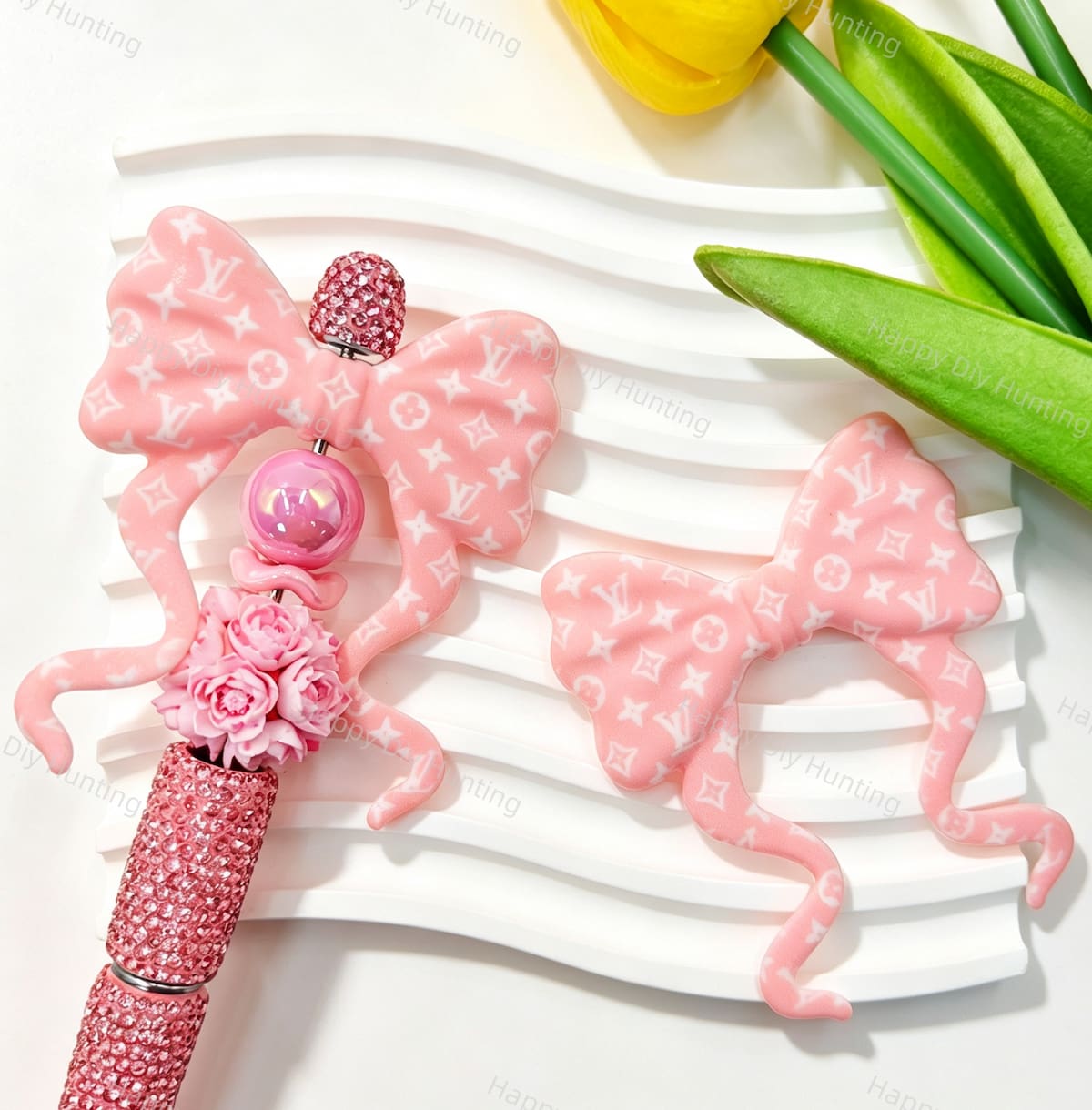 Long tail bow silicone focal beads featuring a pink monogram V*L print design. Soft, durable, and flexible, perfect for beadable pens, keychains, and handmade crafts.