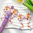 Purple highland cow floral print silicone bow beads displayed with a purple rhinestone beadable pen. Featuring an adorable highland cow with a bow and purple flowers. Soft, durable, and perfect for beadable pens, keychains, and handmade crafts.