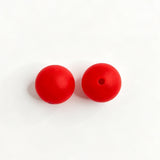 Red round silicone bead shown from two angles, one smooth side and one with a center hole. Soft, durable, and flexible, perfect for beadable pens, keychains, and handmade crafts.