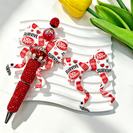 Bow-shaped silicone focal beads featuring a red and white soda brand print design. Soft, durable, and flexible, perfect for beadable pens, keychains, and handmade crafts.