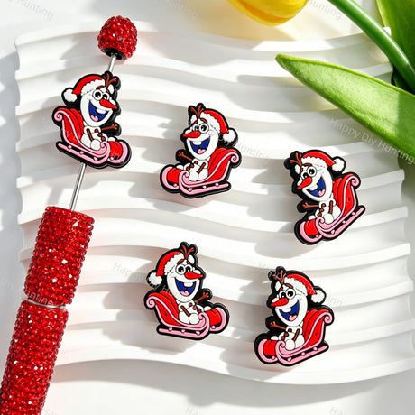 Silicone focal beads featuring a snowman with a Santa hat riding a sleigh print design. Soft, durable, and flexible, perfect for beadable pens, keychains, and handmade holiday crafts.