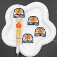 Three identical 'Spooky Vibes' pumpkin patch enamel pins are displayed on a white cloud-shaped tray next to a yellow and white pen, set against a dark gray background.