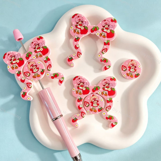 Bow-shaped silicone focal beads featuring a cute strawberry girl character print design. Soft, durable, and flexible, perfect for beadable pens, keychains, and handmade crafts.