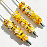 Close-up of four yellow bear cartoon character beadable pens on a white background. Each pen features yellow beads decorated with bear faces, honey pots, bees, white flowers, and clear rhinestones, paired with silver metal tips. Ideal for DIY beadable pen projects, focal beads, and pen toppers.