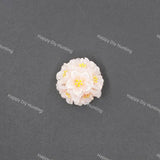 A small white and pale pink flower-shaped accessory with yellow centers, photographed on a dark gray textured background with repeated Happy DIY Hunting watermarks.