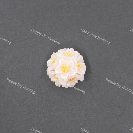 A small white and pale pink flower-shaped accessory with yellow centers, photographed on a dark gray textured background with repeated Happy DIY Hunting watermarks.