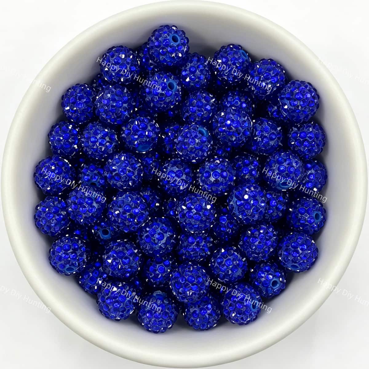 Dark blue rhinestone beads in matte white bowl, white background, top‑down view, high‑resolution product photo